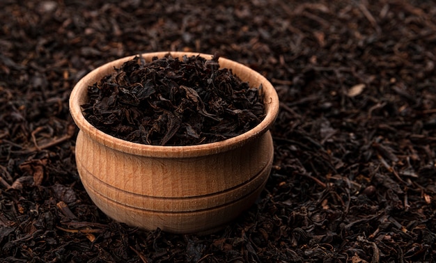 Dry tea leaves in wooden bowl