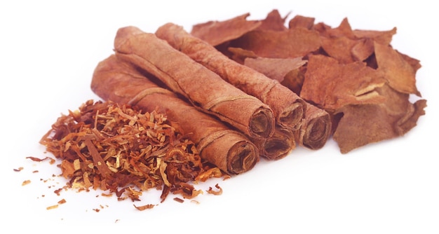 Dry tobacco leaves with hand made cigarette over white background