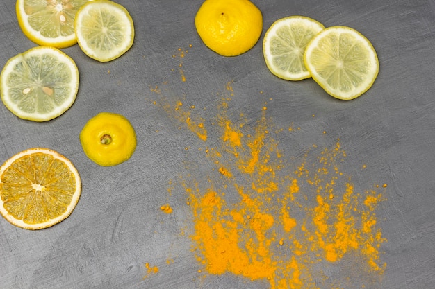 Dry turmeric and lemon slices on a gray background