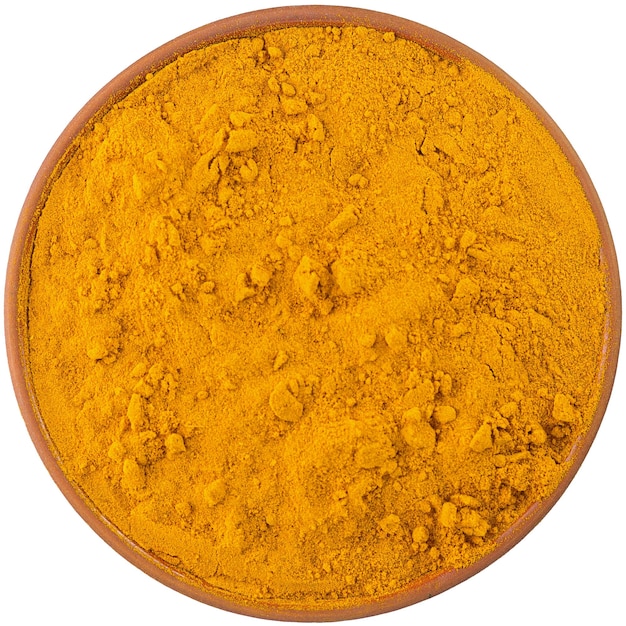 Photo dry turmeric powder in a brown ceramic bowl isolated on white background