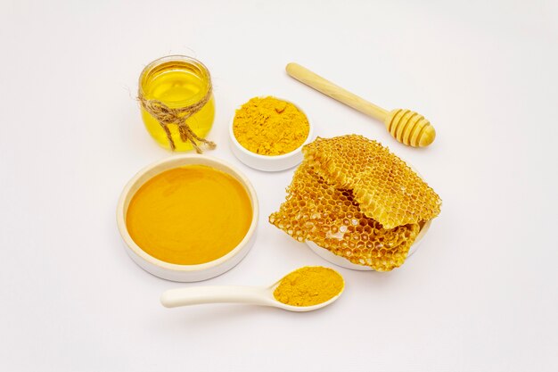 Dry turmeric powder, honey and honeycombs isolated on white background