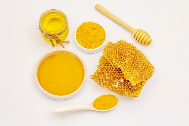 Dry turmeric powder, honey and honeycombs isolated on white background