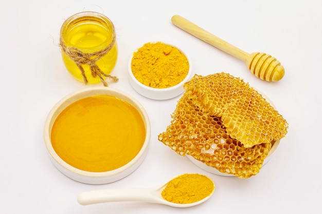 Dry turmeric powder, honey and honeycombs isolated on white background