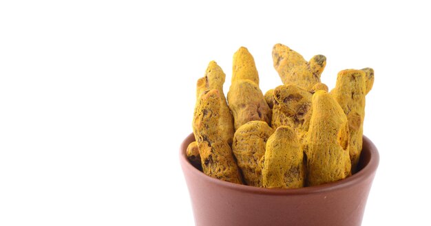 Photo dry turmeric roots or barks in clay pot isolated on white background