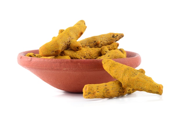 Dry Turmeric roots or barks in clay pot isolated on white surface