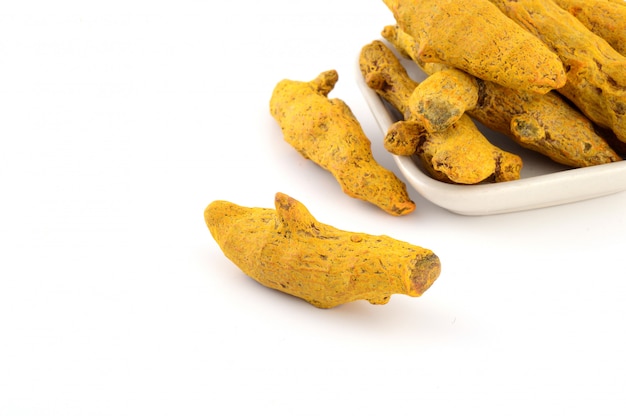 Dry Turmeric roots or barks in white plate isolated on white space