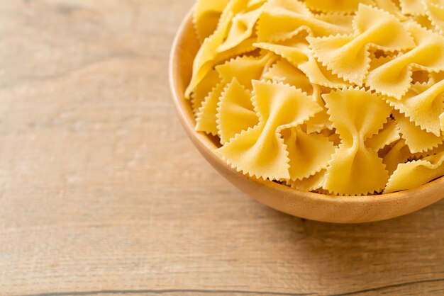 Dry uncooked farfalle pasta in wooden bowl