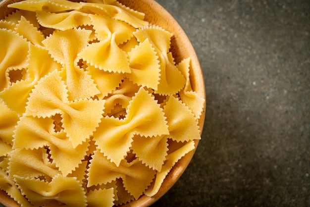 Dry uncooked farfalle pasta in wooden bowl