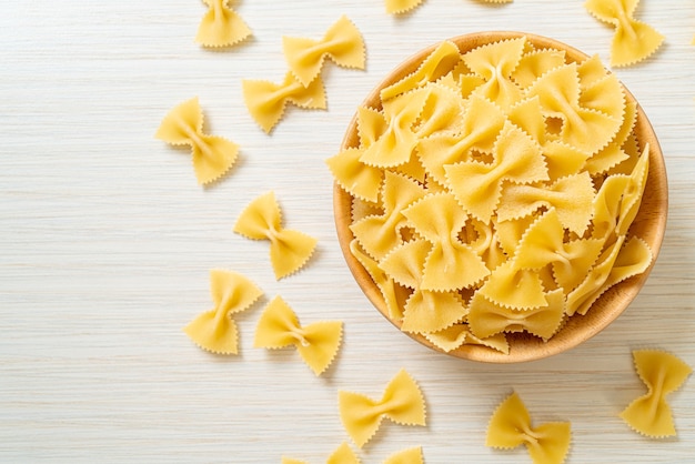 Dry uncooked farfalle pasta in wooden bowl