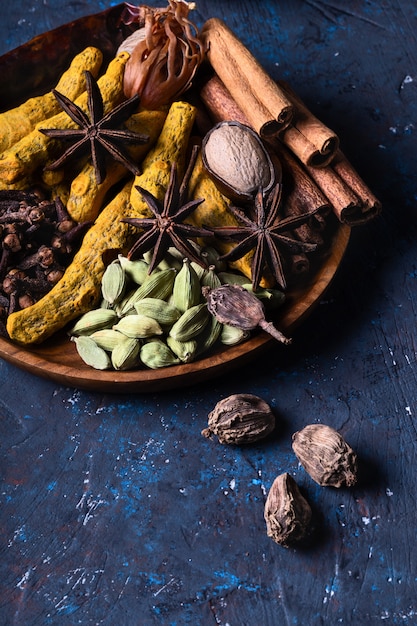 Dry warming Indian spices in on plate for autumn winter meal on dark blue concrete.