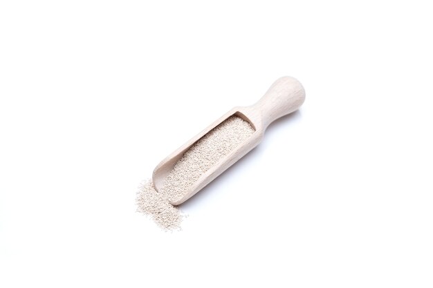 Dry Yeast Granules in wooden scoop on white background Selective focus copy space