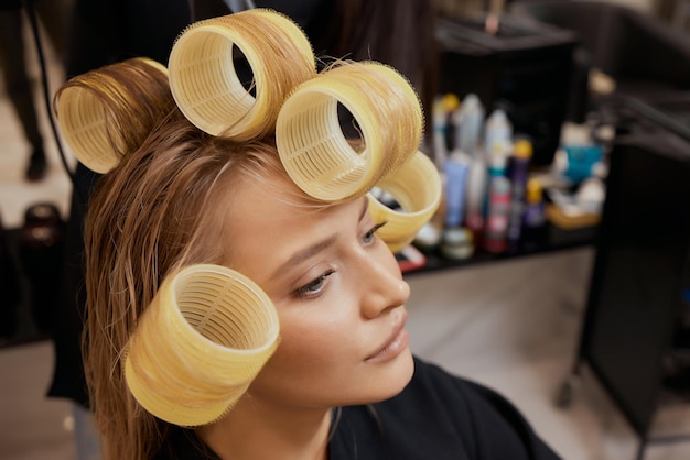 Drying blond hair with hair dryer and round brush.