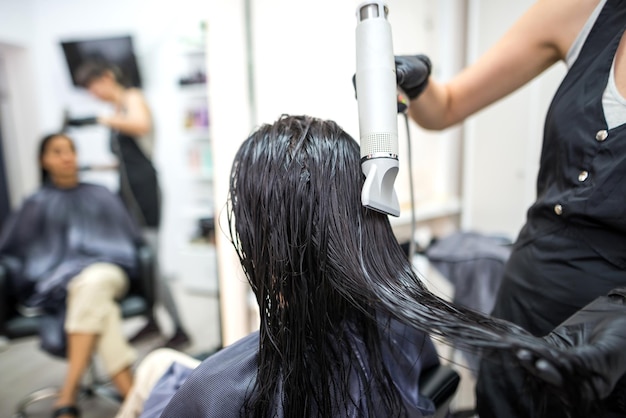 Photo drying long dark hair with a hairdryerprofessional hairdresser dries the hair of a client in the salon hairstyle beauty hair care fashion service