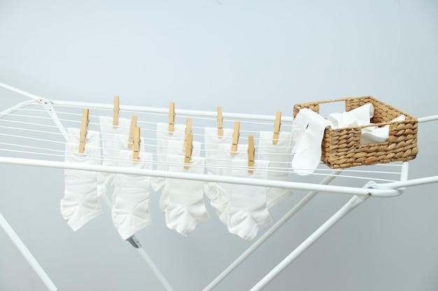 Drying rack with white socks and wicker box with socks on light\
background