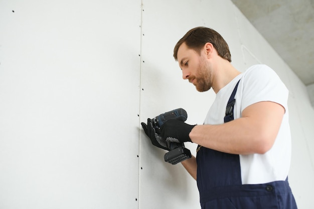 drywall worker works on building site in a house