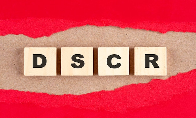 DSCR word on wooden cubes on red torn paper financial concept background