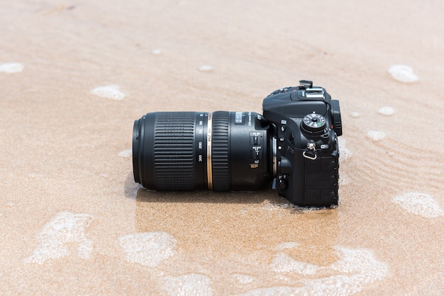 DSLR-camera op strand nat van water overzeese golf