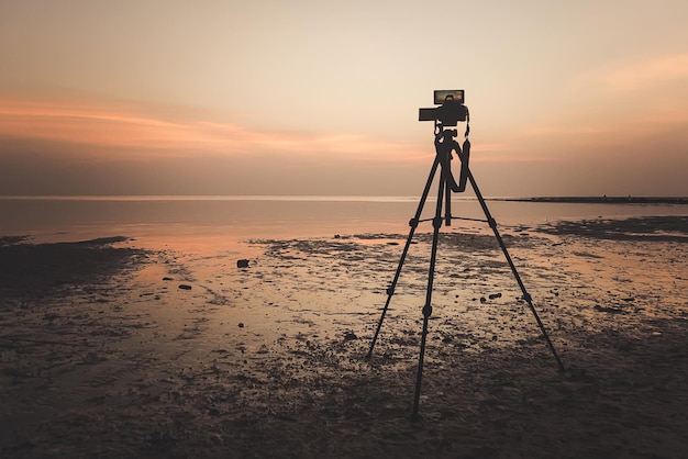 Dslr digital professional camera stand on tripod photographing sea twilight sky