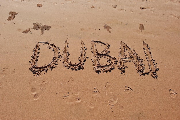 Dubai geschreven in het zand op het strand