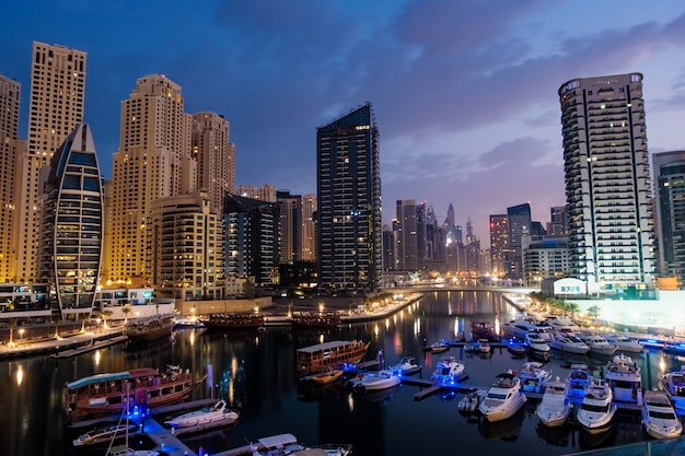 Dubai marina with boats and buildings at night, United Arab Emirates