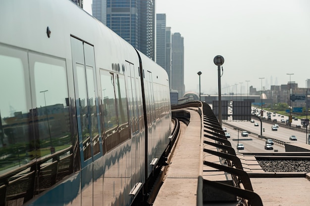 두바이 아랍 에미리트 2021년 11월 8일 고층 빌딩의 배경에서 레일에 두바이 지하철 기차 유명한 야외 지하철 레드 라인