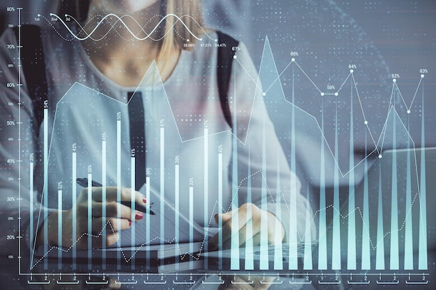 Dubbele blootstelling van zakenvrouw handen typen op computer en financiële grafiek hologram tekening Stock market analysis concept