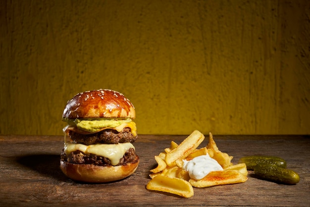Dubbele cheeseburger en frietjes op een houten tafel.