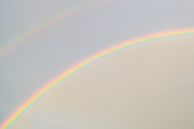 Dubbele regenboog in de lucht. na de regen. natuurlijk wonder. bewolkte hemel op een regenboog achtergrond. een symbool van vrede. en lgbt