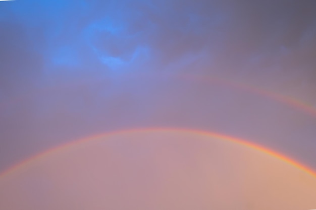 Dubbele regenboog in donkere lucht na regen