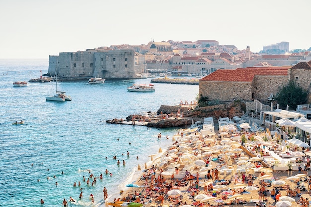 Dubrovnik, Kroatië - 18 augustus 2016: Mensen op het strand van Banje en het oude fort in de Adriatische Zee, Dubrovnik, Kroatië.