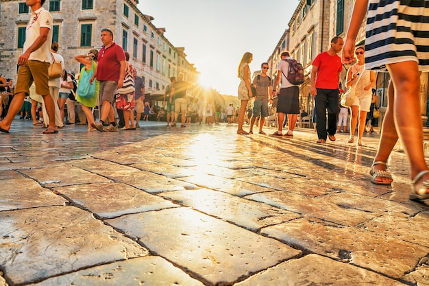 Dubrovnik, Kroatië - 20 augustus 2016: Menigten van mensen op Stradun Street bij zonsondergang in de oude stad van Dubrovnik, Kroatië. Zon weerspiegeld in steen.