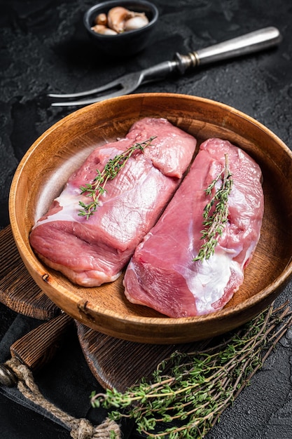 Duck breast fillet in wooden plate raw poultry meat steaks Black background Top view