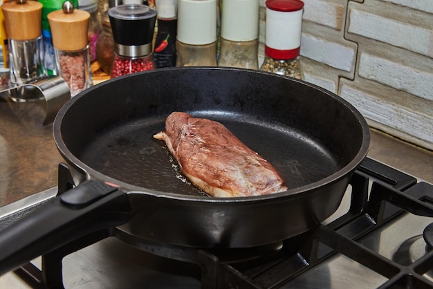 Duck breast is fried in frying pan on gas stove