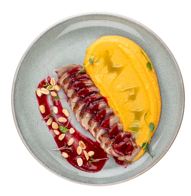 Фото Уткая грудь с тыквенным пюре, вишневым соусом и арахисом изолированное изображение