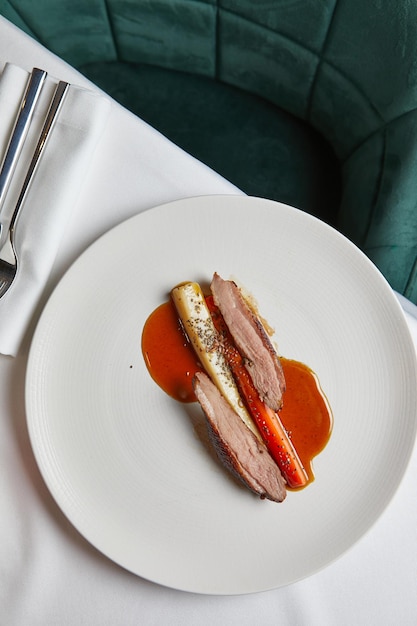 Duck fillet with vegetables in sweet and sour sauce on a white plate top view