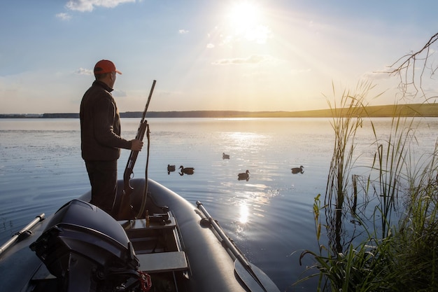 Duck Hunter in boat on a sunset background Hunter in boat hunting ducks