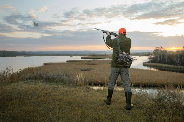 Duck Hunter - watervogeljager die in vliegende eend schiet tijdens eendenjacht bij zonsopgang