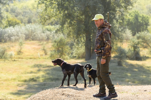 Duck hunter with shotgun walking through a meadow.