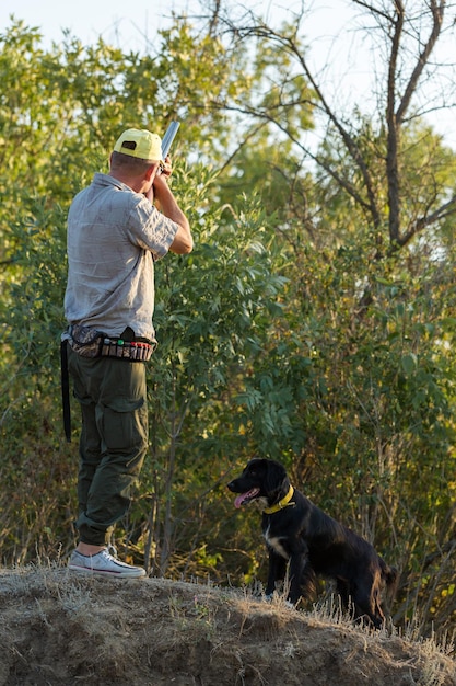 Duck hunters with shotgun walking through a meadow