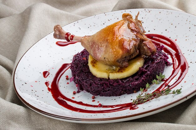 Duck leg with apple and cabbage on textile background