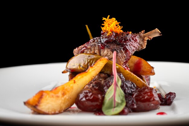 Duck leg with pear on a white plate