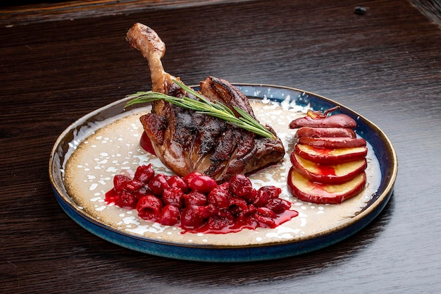 Duck leg with winecherry sauce and baked apple On a wooden background