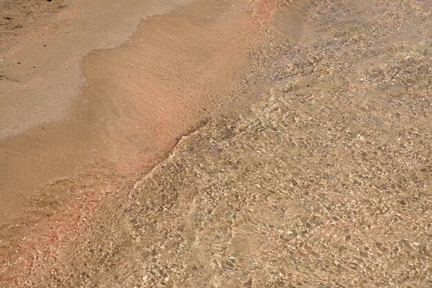 Duidelijke golven en kleurrijk zand op tropisch zandstrand in Kreta Griekenland.