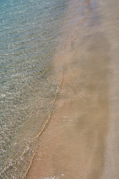 Duidelijke golven en kleurrijk zand op tropisch zandstrand in Kreta Griekenland.