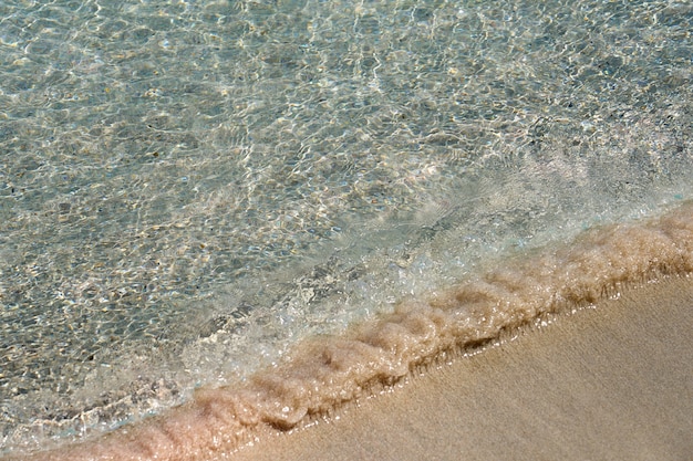 Duidelijke golven en kleurrijk zand op tropisch zandstrand in Kreta Griekenland.