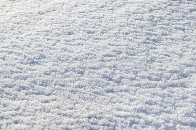 Duidelijke sneeuwtextuur in fel zonlicht, winterachtergrond met sneeuw