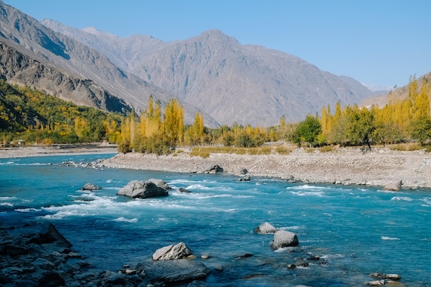 Duidelijke turkooise blauwe waterrivier die langs Hindu Kush-bergketen in de herfst stromen.