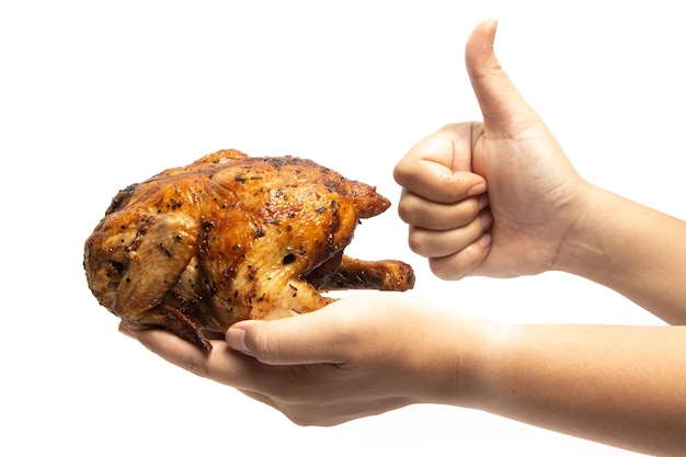 Foto duim en hand die een hele heerlijke geroosterde kip vasthouden die is gekruid met geïsoleerde kruiden