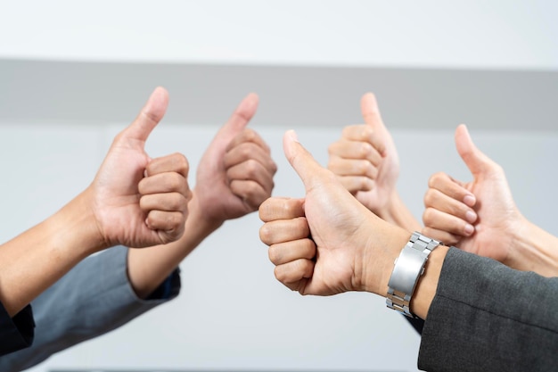 Foto duim omhoog met de handen van een bedrijfsteam of groep die hun goedkeuring geven, bedankt zeggen of motivatie geven samen in hun kantoor op het werk