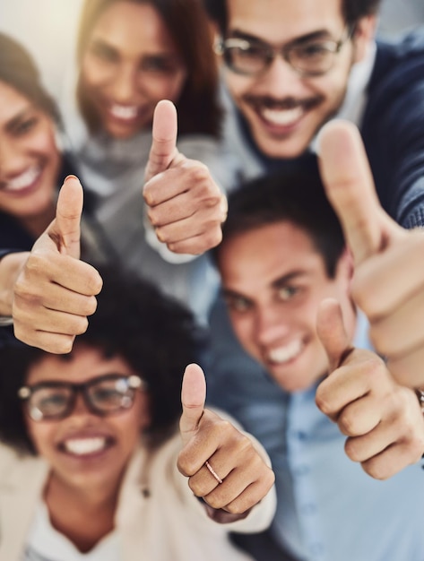 Foto duim omhoog van een gelukkig zakelijk team enthousiast over het succes dat ze samen op het werk behalen bovenaanzicht diverse groep bedrijfsmensen enthousiast over succes en goedkeuring geven aan winnen